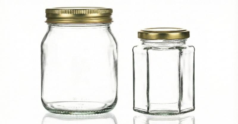 a traditional 1 lb screw off honey jar next to a 280 ml hexagonal twist off jar