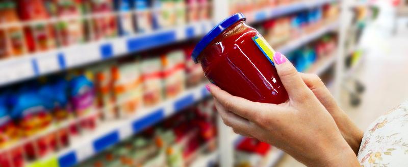 A woman choosing a jar with a product inside in a supermatket