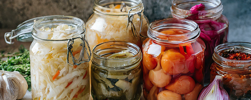 Pickling jars filled with preserves and pickles on a pantry table