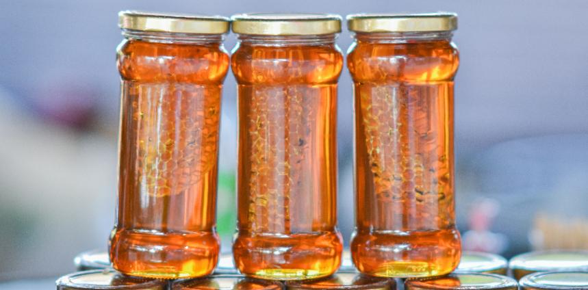 three jars with lids filled with honey, bulk glass jars for your product